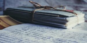 Stack of vintage letters and photographs tied with string on a rustic wooden table.